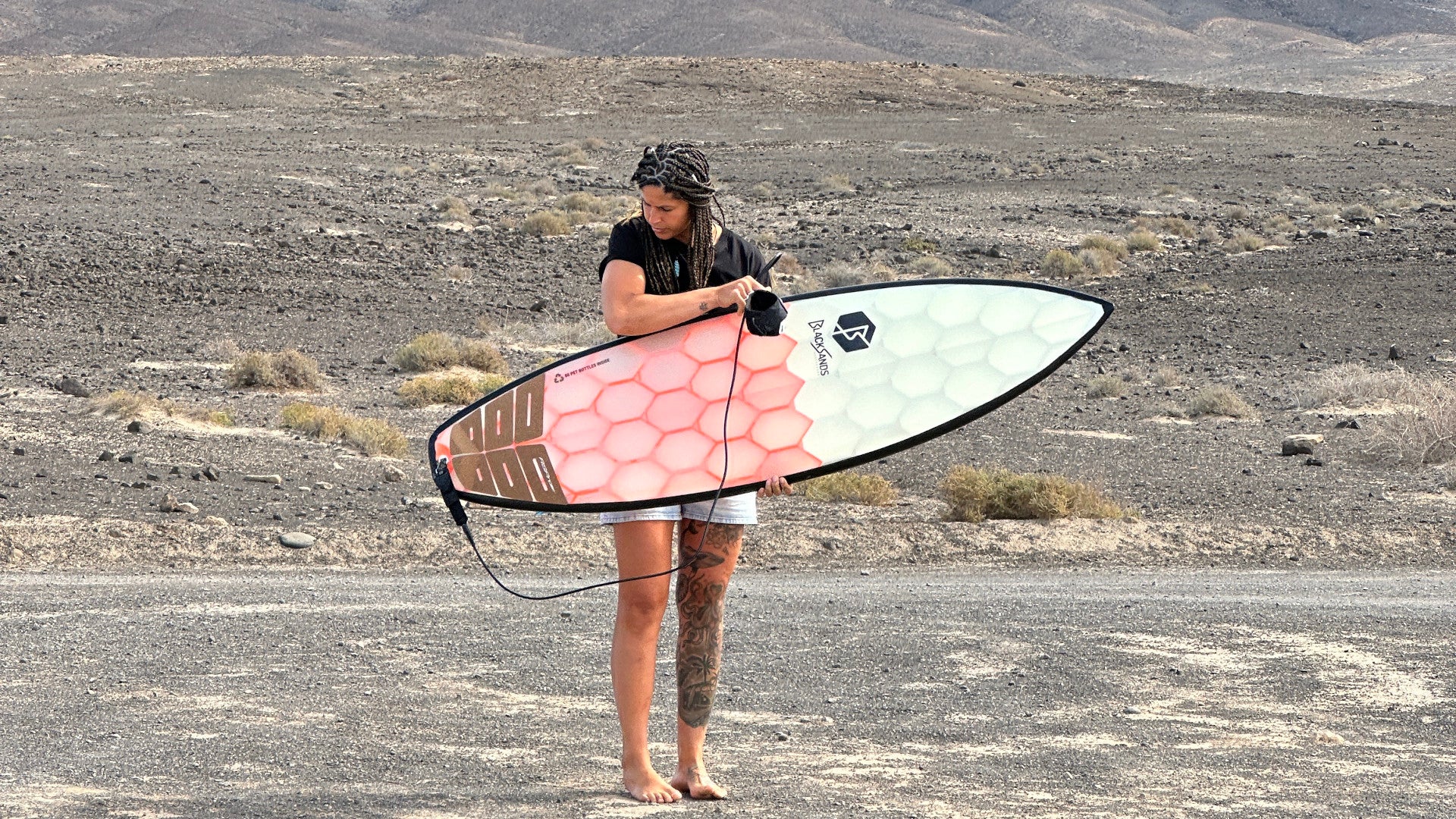 Black Sands orange board in hand of a surfer